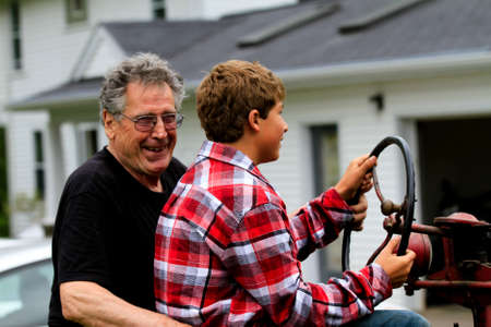 Grandfather teaching his Grandson how to drive a stick shift on a Tractorの写真素材