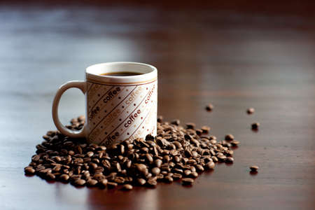Mug that Says Coffee and Beans on a  table.の写真素材