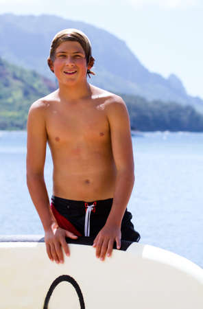 Paddle Surfing Kauai a Teenage boy and his board on the beachの写真素材
