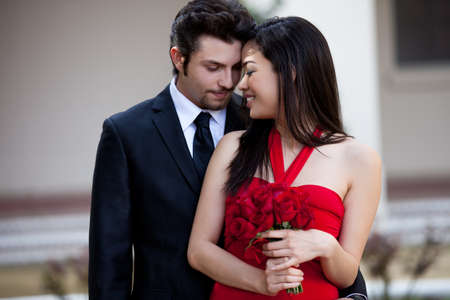 Beautiful Asiian Woman with Red Roses in a Red Dress with her Lover looking at herの写真素材