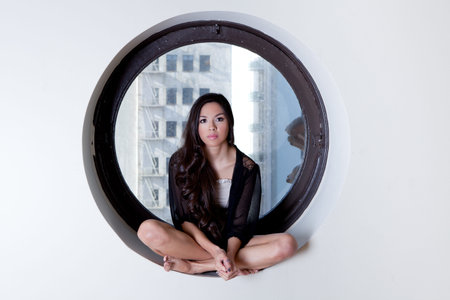 Pretty Hispanic Woman wth Beautiful Long Hair sitting in the quiet space of a circle window