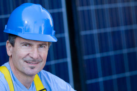 Man in his forties overseeing a Solar Instalation in front of Solar panelsの写真素材