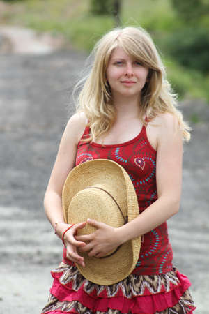 Pretty Blonde Girl holding her hat in the countryの写真素材