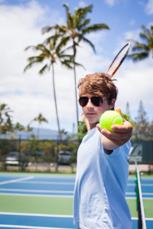 A Handsome Teenager offers the Tennis Ball to viewer while in Hawaiiの写真素材