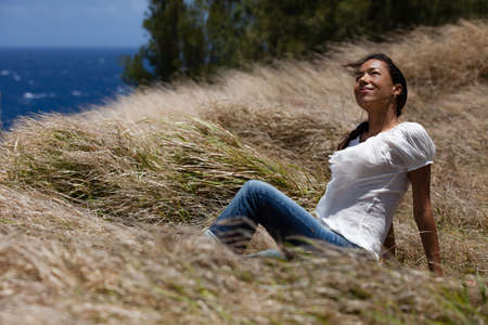Casual Pretty Woman looking up with a smile at the oceanの写真素材