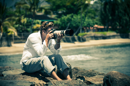 Man itting on Lava rocks taking pictures in Hawaii