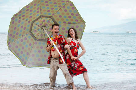 Tourist in matching outfits dancing with an Umbella in Hawaiiの写真素材
