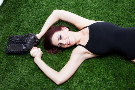 Beautiful Woman holding a baseball and glove on Grassの写真素材