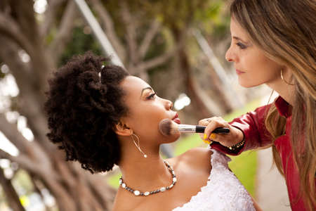 Beautiful Bride and her Makeup artist adjusting her eye shadowの写真素材