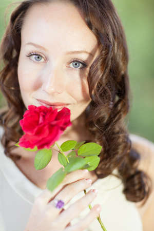 Pretty Woman with beautiful blue eyes and a red rose looking at cameraの写真素材