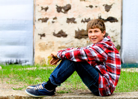 Teen sitting in front of an old vintage stone barn wallの写真素材
