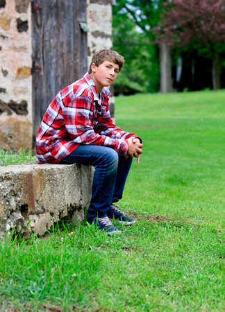 Teen sitting in front of an old vintage stone barn wallの写真素材