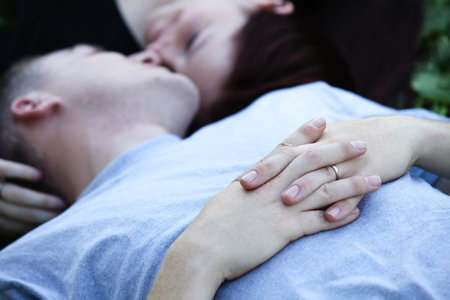 A couple smiling very close  lying down low angle view focus on the wedding bandの写真素材
