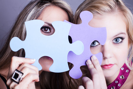 Two Beautiful women looking through game pieces at camera