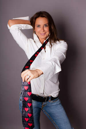 Happy Brunette Beautiful Woman wearing a necktie with hearts and XOXO on itの写真素材