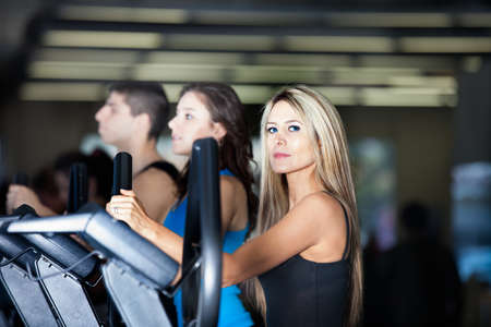 Beautiful Woman with long hair and her friends at the Gym on stair steppersの写真素材