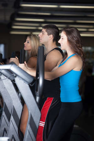 Attractive young woman in Blue at the Gym on stair steppers and two friendsの写真素材