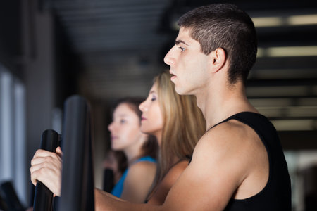 Attractive muscular man exercising with women at the gym