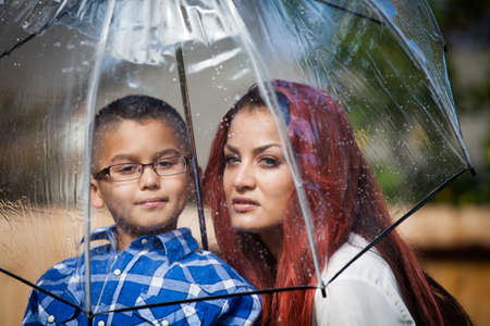 Mother and her son in the rain on a sunny day under an umbrellaの写真素材