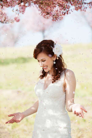 Beautiful laughing bride showered by cherry blossom confettiの写真素材