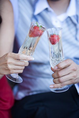 Champagne with strawberries in the forefront of a romantic couple toastingの写真素材