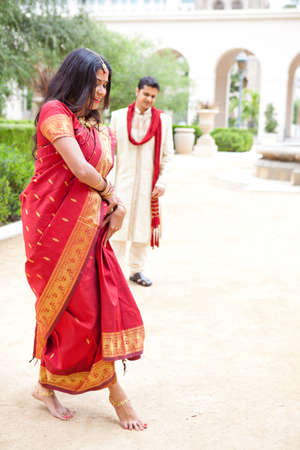 Gorgeous Indian bride dancing as her husband looks onの写真素材