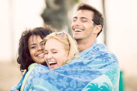 Friends at Sunset on the Beach in California wraped in a towel together