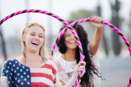 Young women Friends on the boardwalk at the Beach playing with Hula Hoopsの写真素材