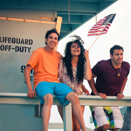 Young Group of Friends at the Beach at Sunset with American Flagsの写真素材