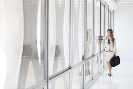 Beautiful Business Woman looking out Glass windoew with a briefcaseの写真素材