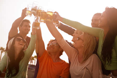 Sunset on the Boardwalk with friends at the beach cheering with Beer at a Bistroの写真素材