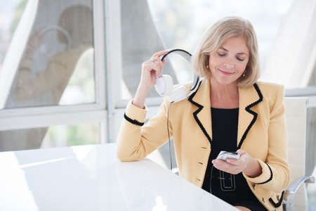 Beautiful fifty year old woman enjoying music with her noise canceling headsetの写真素材