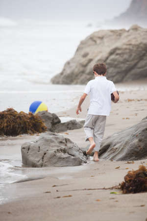 Child running on the beach with beach Ballの写真素材