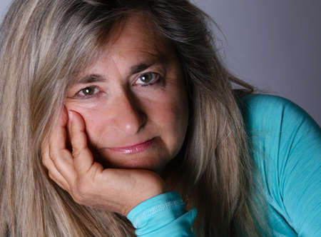 Attractive woman with long hair in her mid fifties looking at you shot in studioの写真素材