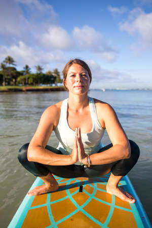 Pretty young woman in prayer pose on the water at Ala Moana state park Oahu Hawaiiの写真素材