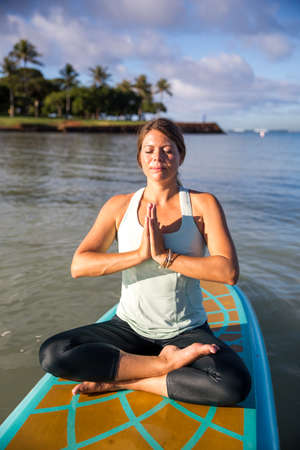 Pretty young woman in meditation on the water at Ala Moana state park Oahu Hawaiiの写真素材