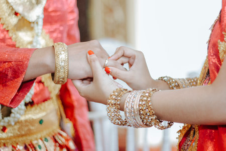 A close up of the bride's hand is seen putting the ring on the groom's fingerの写真素材