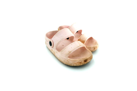 The girl's dirty pink slippers on a white backgroundの写真素材