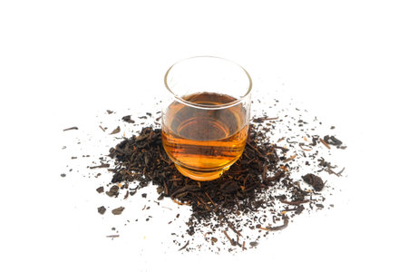 a glass of tea on dry black tea leavesの写真素材