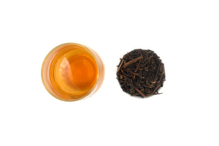 a glass of tea and a small cup of black tea leaves next to itの写真素材