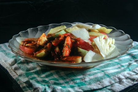 Fresh slice tropical fruits with hot peanut dressing called rujak buah in indonesia for healthy dessert put on the table in round plateの写真素材