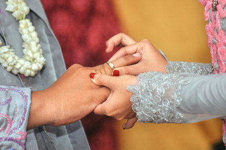 closeup of the bride's hand putting the ring on the groom's handの写真素材