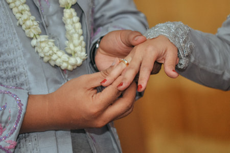 closeup of the groom's finger putting the ring on the brideの写真素材