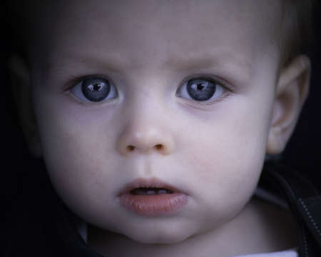 A young boy stares intently into the cameraの写真素材