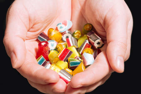 Big handful of handmade mix lollipops multicolored in the hands of young girlの写真素材