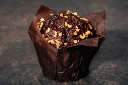 Coffee and chocolate muffin with nuts in paper. Low key. Black background. Breakfast conceptの写真素材