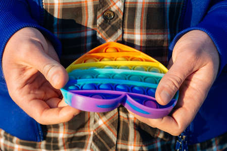 colorful antistress sensory toy fidget push pop toy in man hand.の写真素材