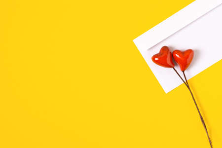 top view love letter, white envelope with red hearts on yellow background. white letter with copy space flat layの写真素材