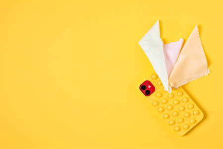 Top view cleaning smart phone screen on yellow background. Flat lay cleaning yellow phone by fabric microfiber conceptの写真素材