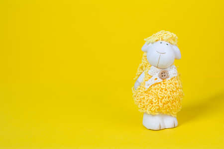 Baby toy sheep on a yellow background with copy space. Cute children toy white yellow sheep on colored background. Baby toys conceptの写真素材